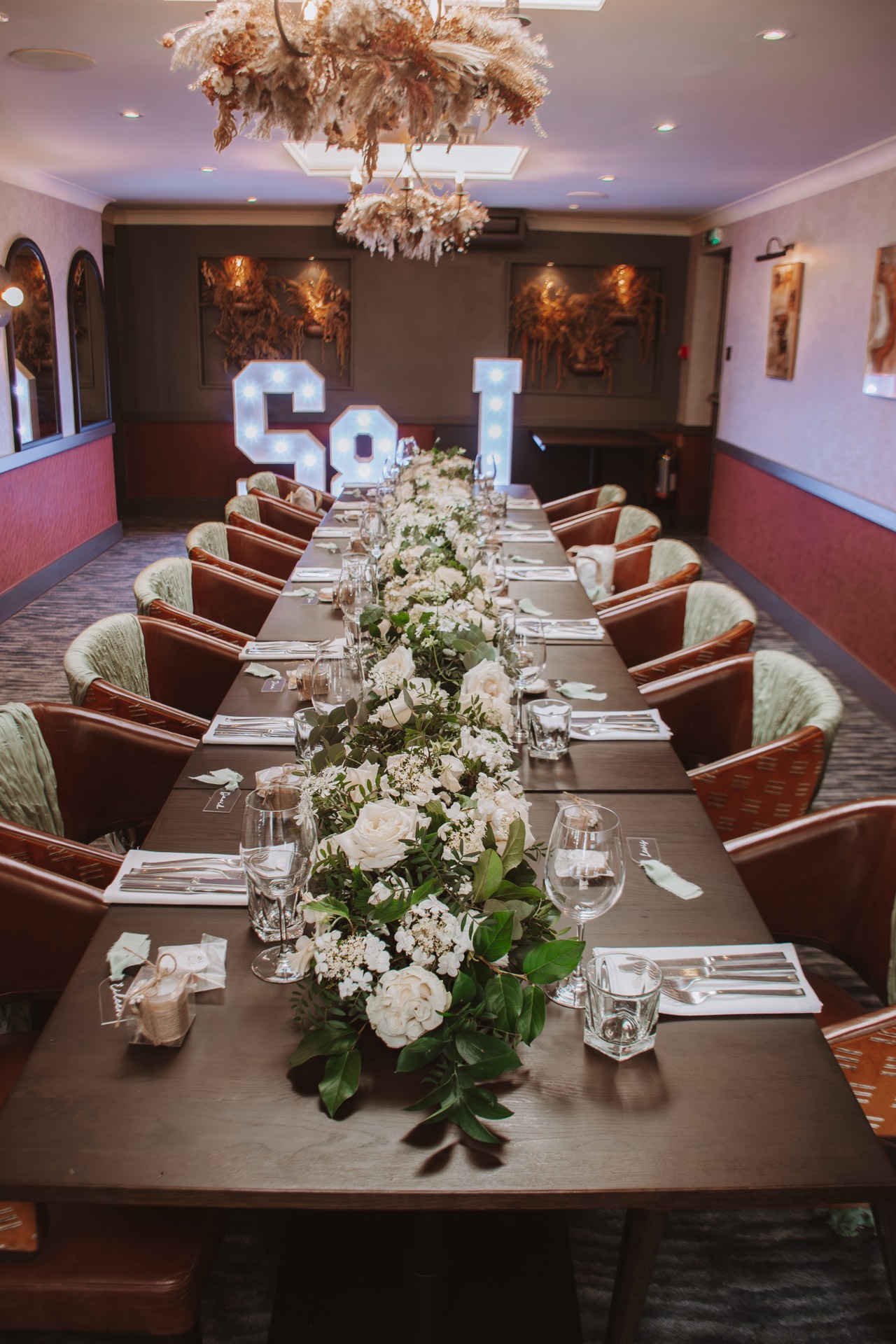 An elegant dining table set for an event, decorated with white flowers and greenery