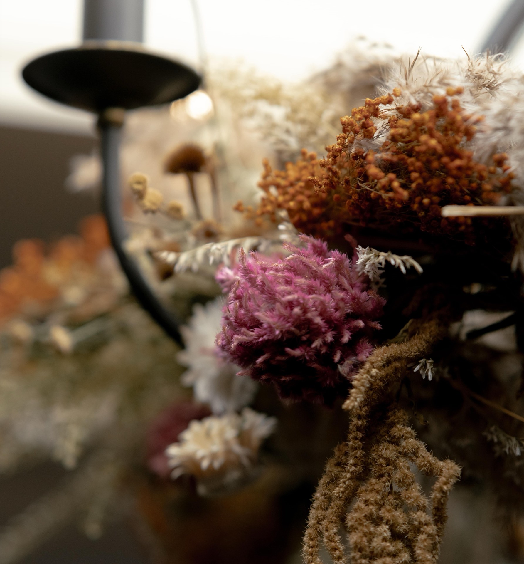 A dried flower arrangement beside a candle sconce at Mason's
