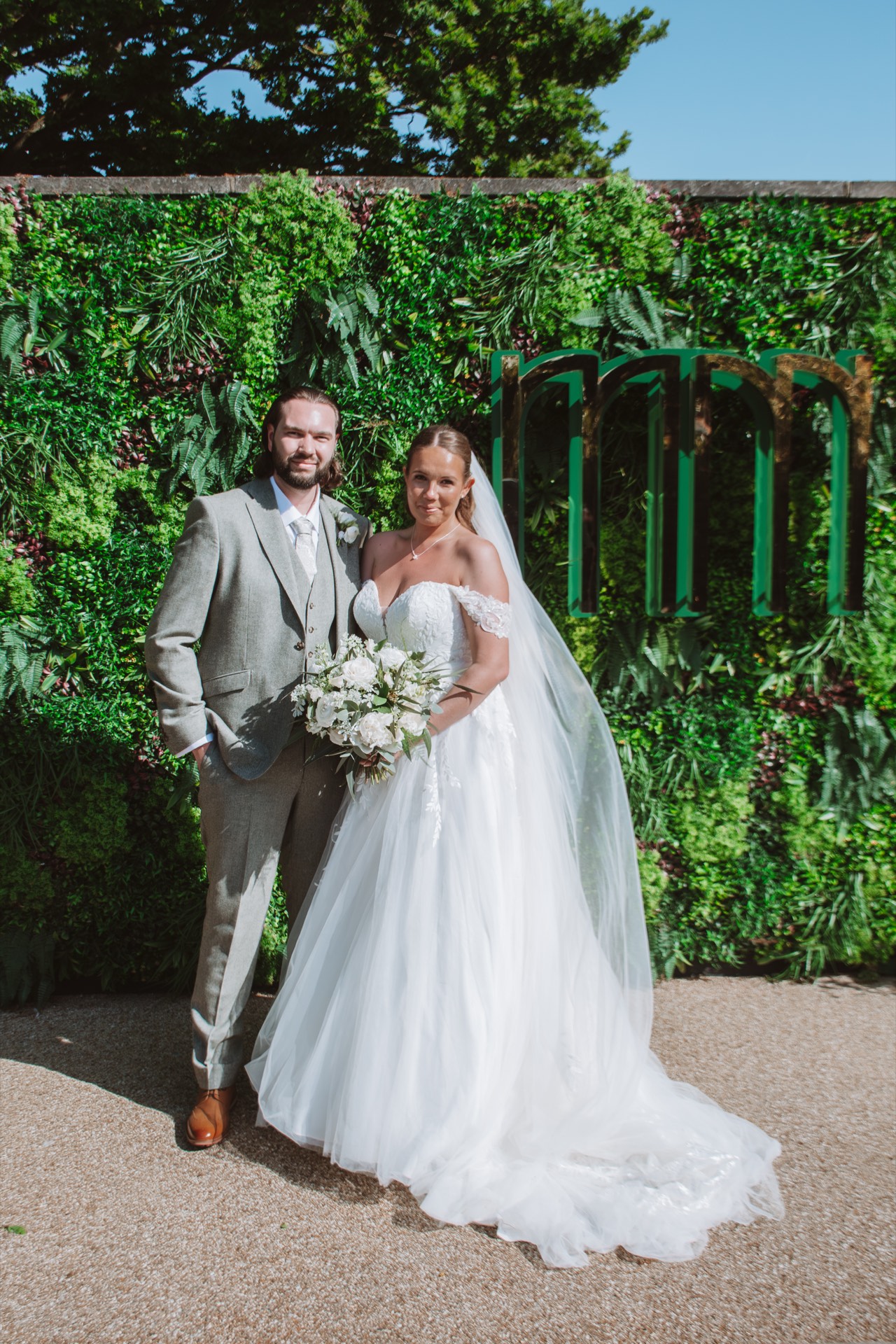 A bride and groom outdoors with a green leafy backdrop