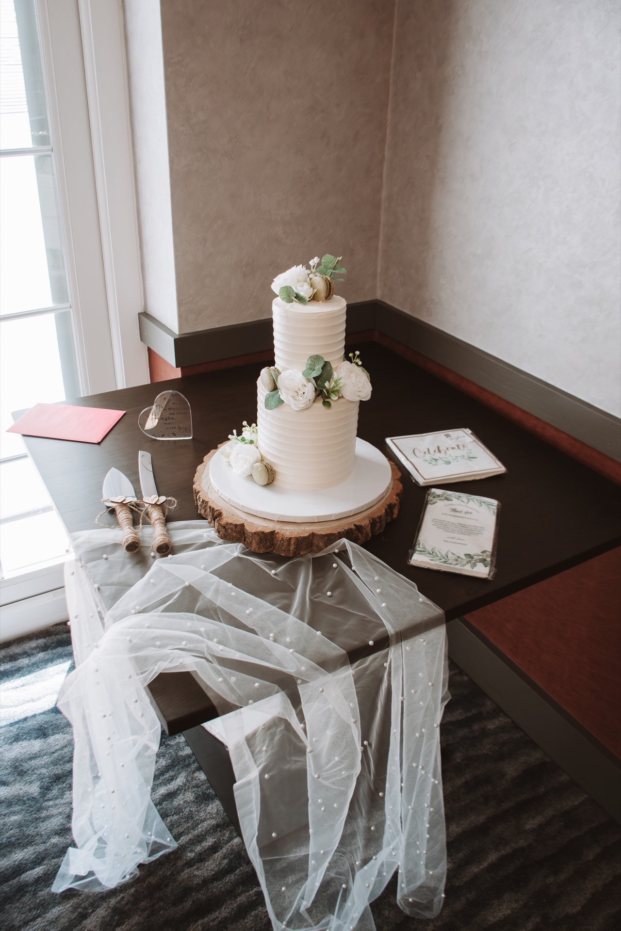 An elegant two-tier white wedding cake with flowers and greenery